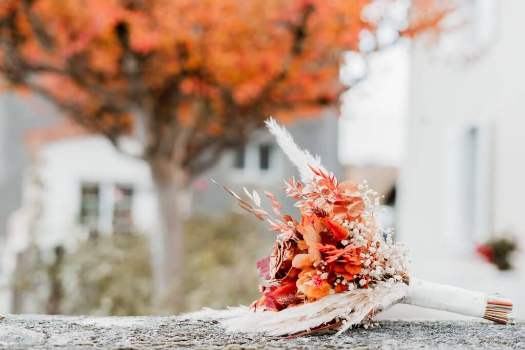 Bouquet de fleurs séchées, aux couleurs de l'automne, posé sur un mur
